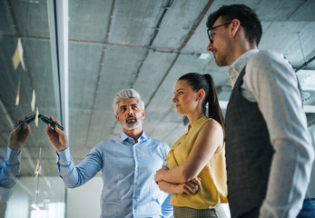 A group of business people standing in an office, brainstorming.