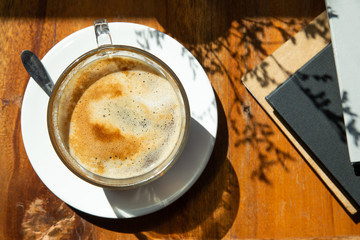 Top view of coffee cup on a wood table with morning light by the window
