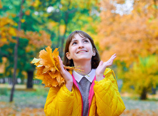 teen girl posing with autumn leaves in city park, outdoor portrait