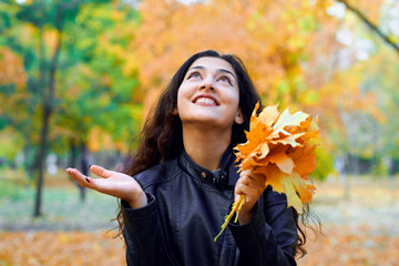 woman posing with autumn leaves in city park, outdoor portrait