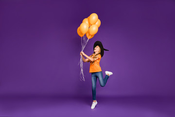 Full body photo of little witch lady halloween party holding air balloons making spell to make them...