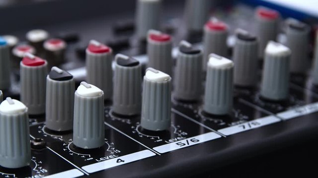 Tracking left shot of a audio mixer desk with many buttons