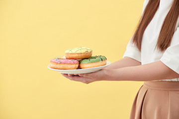 Asian girl show and holding plate full of tasty delicious aromatic donuts in smile face isolated.