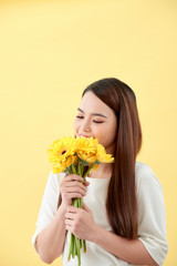 Asian lady holding a bunch of flower standing against a wall