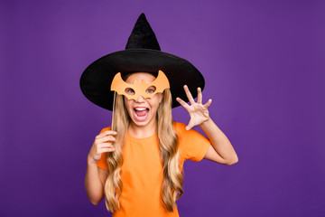 Photo of little witch lady playing paranormal creature halloween theme party holding bat paper stick wear orange t-shirt wizard hat isolated purple color background