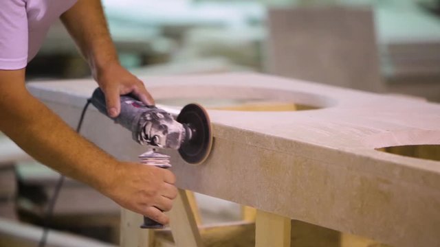 Natural stone manufacturing plant. Worker hand polishing a piece of stone