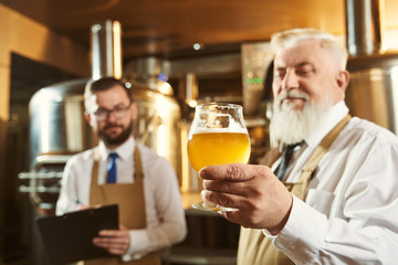 Experts examining beer at factory.