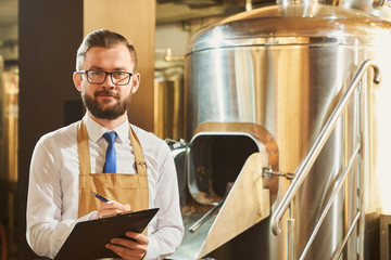 Expert of brewery holding folder, posing, looking at camera.