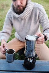 young man pours coffee from a geyser coffee maker