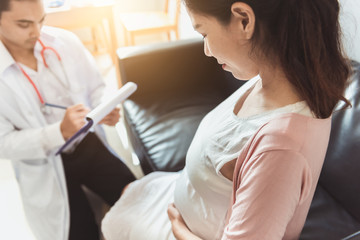 Fototapeta premium The gynecologist holds a checklist for pregnant women for pregnancy consultant, Doctor examine pregnant belly and mother healthcare check up, Gynecology concept.
