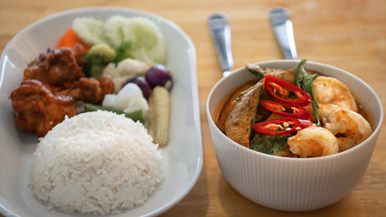 food background of Thai style food set menu of spicy and sour yellow curry with acacia vegetable omelette served with deep fried chicken wing sticks, rice and variety of fresh vegetable