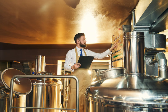 Handsome engineer of brewery inspecting process of brewing.