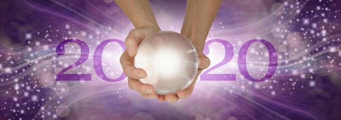 Experience a Crystal Ball Reading - What does 2020 hold for you - female hands holding a large clear crystal ball between 20 and 20 making 2020 against a wide purple sparkling flowing background 