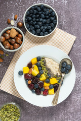 Healthy breakfast with oatmeal porridge, fruits and nuts. Blueberry, mango, pumpkin seeds, nuts, coffee cup. Top view. Clean eating, dieting, weight loss concept