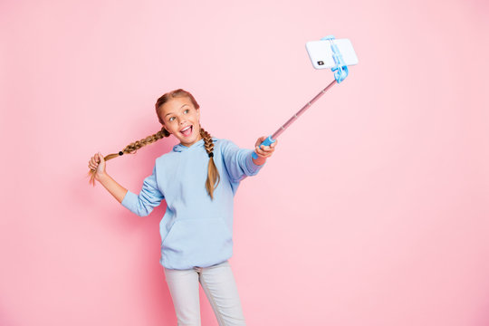 Photo of pretty little lady holding metal stick mono pod making selfies for youth famous blog wear casual blue hoodie pullover isolated pastel pink color background