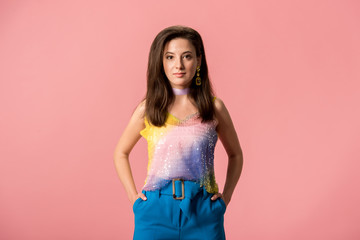 young stylish disco girl with hands in pockets isolated on pink