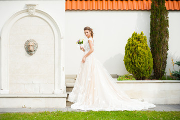 Beautiful happy bride in long wedding dress with wedding bouquet