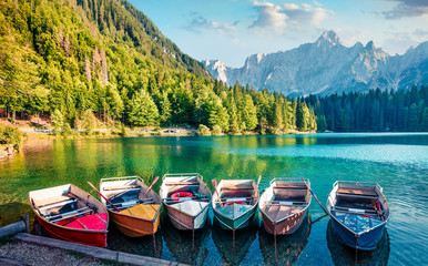 Six pleasure boats on Fusine lake. Colorful evening scene of Julian Alps with Mangart peak on background, Province of Udine, Italy, Europe. Traveling concept background. - obrazy, fototapety, plakaty
