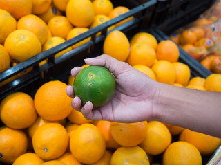 Fresh orange fruits in the basket for sale.Healthy fruit at the organic market.Buyer's hand choosing orange from the food counter at the supermarket.