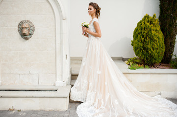 Beautiful happy bride in long wedding dress with wedding bouquet