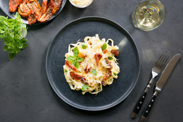 Pasta tagliatelle with dried tomatoes and oregano on black. Delicious Mediterranean lunch.