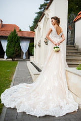 Fototapeta premium Beautiful bride in long wedding dress with bouquet