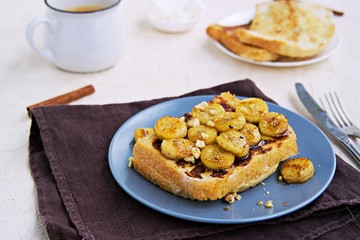 Breakfast, french toasts with banana, walnuts and honey on a gray plate on a light concrete background. French cuisine