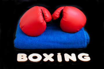 Red boxing gloves, a towel and the inscription of the wooden letters 