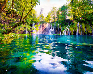 Last sunlight lights up the pure water waterfall on Plitvice National Park. Spectacular spring scene of green forest with blue lake. Wonderful countryside view of Croatia, Europe.