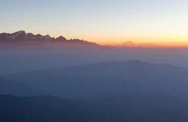 Fototapeta na wymiar Misty landscape in himalayas. Foggy mountain ridges on sunrise. Beautiful view on everest base camp trail.