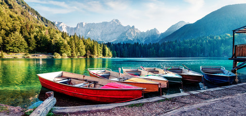 Six pleasure boats on Fusine lake. Panoramic evening scene of Julian Alps with Mangart peak on...