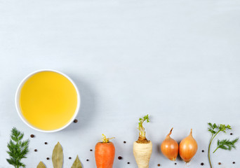 Broth in the plate on the gray background.