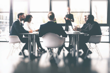 Background concept with business people sitting at the meeting table in the office near a window...