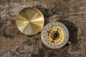 Golden vintage compass on wooden background with natural light