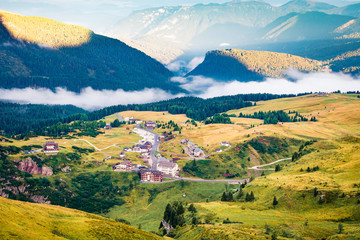 Aerial morning view of the top of Rolle pass. Picturesque summer scene of Dolomites. Foggy landscape of mountain valley, Trentino province, Italy, Europe. Traveling concept background.