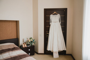 Fototapeta na wymiar Modern bridal fashion. White wedding dress hanging in the hotel room.