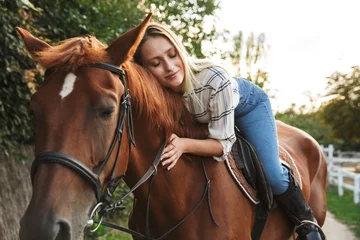 Foto op Canvas Smiling attractive young blonde girl riding a horse © Drobot Dean