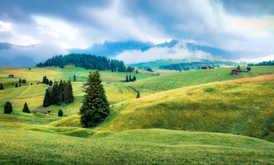 Foggy morning scene of Compaccio village, Seiser Alm or Alpe di Siusi location, Bolzano province, South Tyrol, Italy, Europe. Picturesque summer view of Dolomiti Alps.