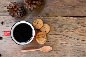 Red cup of coffee, a cookie placed beside an old wooden floor.