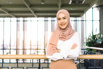 Portrait of casual young muslim woman wearing hijab headscarf in cafe.