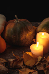 dry foliage, burning candles, ripe pumpkin on wooden rustic table isolated on black