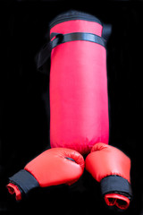Red boxing gloves and a boxing bag for punches on a black background