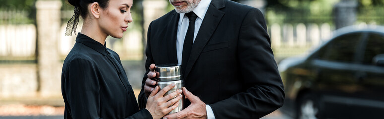 panoramic shot of man and woman holding mortuary urn