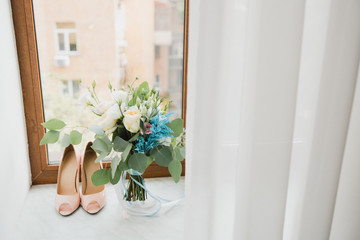 Beautiful modern bridal bouquet of colorful fresh flowers with sikl ribbons. Classic wedding traditional accessory. Leather female shoes standing near it.
