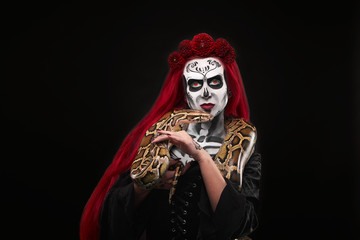 Woman with sugar skull make up holding serpent.