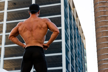 Obraz premium muscular fitness man posing with his back on the street with a building in the background
