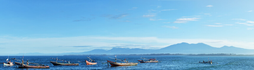 Panoramic beautiful tropical beach with wooden fishing boat and blue sky in the morning at The Bengkulu beach Indonesia.