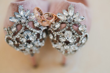 Modern wedding jewelry. Closeup of two wedding rings and engagement ring on female leather shoes.