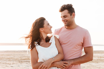 Beautiful young couple wearing summer clothing standing at the beach