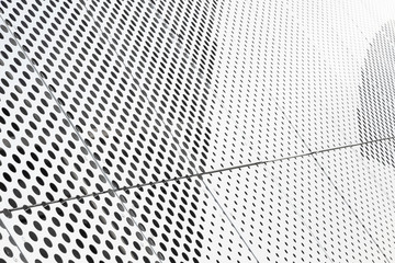 Diagonal view of metall grilles and round holes in metal surface, perforated panels close-up